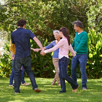 Happy family, holding hands and dance together outdoor or play game in summer in a circle with grandparents. Ring a rosy, smile and children in garden on holiday, vacation and bonding with parents.