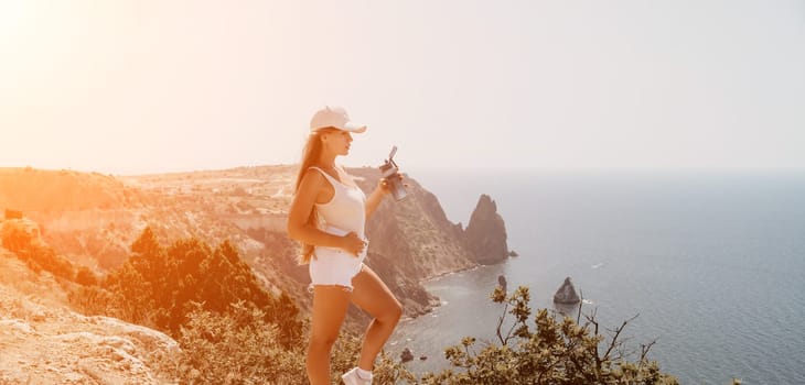 Woman travel sea. Young Happy woman in a long red dress posing on a beach near the sea on background of volcanic rocks, like in Iceland, sharing travel adventure journey