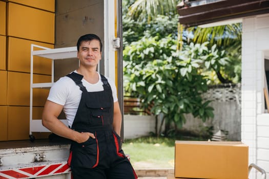 A portrait of a cheerful mover unloading boxes into a new home from a truck. These removal company workers ensure efficient moving spreading joy. Moving day concept