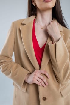 Attractive young female model showcasing elegance in a trendy beige winter coat with a stylish v-neck collar and tailored fit.