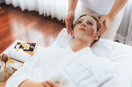 Serene modern daylight ambiance of spa salon, woman customer indulges in rejuvenating with facial skincare mask. Facial skin treatment and beauty cosmetology procedure for face. Quiescent