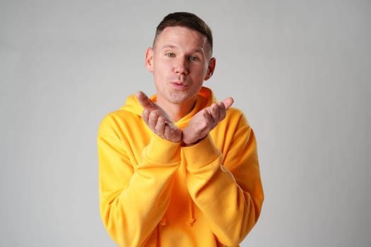 Young man blowing a kiss against gray background studio shot close up