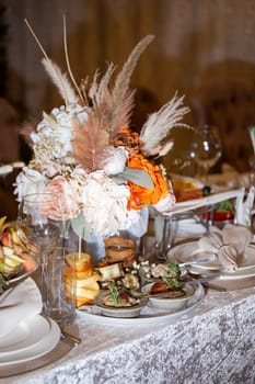 A table adorned with vibrant flowers, elegant glasses, and delicious food, set up for a chic event, exuding sophistication and charm.