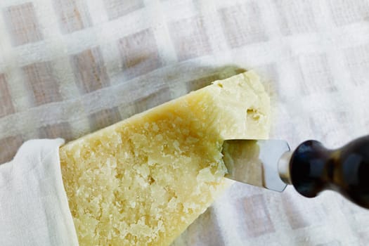 Italian hard cheese Parmesan -Parmigiano Reggiano produced from cow's milk on table with cheese knife