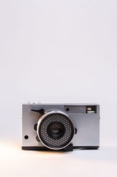 Vintage film camera with a sleek silver body and a classic black manual focus lens, elegantly displayed against a clean white background.