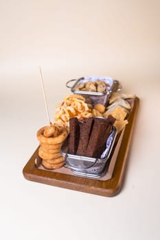 Top view beer platter with croutons, onion rings, chips on a wooden board.