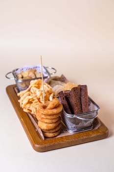 Top view beer platter with croutons, onion rings, chips on a wooden board.