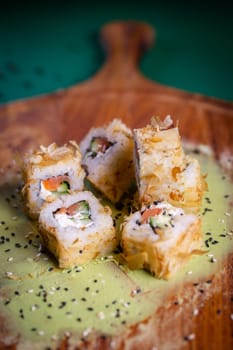 Delectable deep-fried sushi roll with fresh salmon, cucumber, on wooden plate with wasabi and sesame seeds, a Japanese delight.