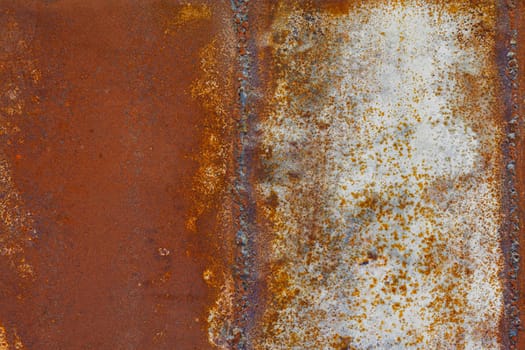 Close up of a brownish rusted welded sheet metal surface with yellowish and orange hue and amber patina.