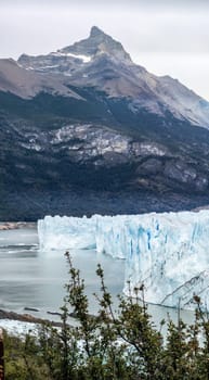 Captivating photo captures a majestic iceberg before mountains, highlighting nature's serene beauty.