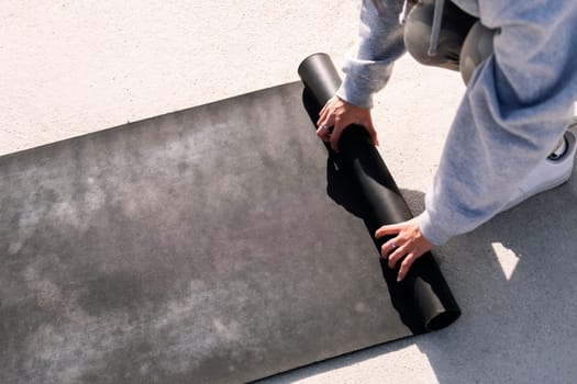 hands of an unrecognizable young woman rolling a yoga mat, healthy and active lifestyle concept, copy space for text