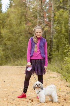 Image of charming little girl walking with puppy in park