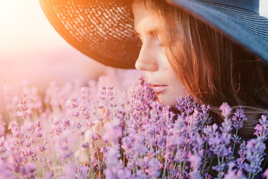 Close up portrait of young beautiful woman in a white dress and a hat is walking in the lavender field and smelling lavender bouquet.