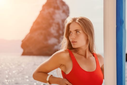 Close up shot of beautiful young caucasian woman with black hair and freckles looking at camera and smiling. Cute woman portrait in a pink bikini posing on a volcanic rock high above the sea