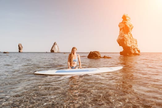 Close up shot of happy young caucasian woman looking at camera and smiling. Cute woman portrait in bikini posing on a volcanic rock high above the sea