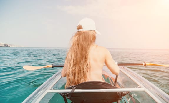 Woman in kayak back view. Happy young woman with long hair floating in transparent kayak on the crystal clear sea. Summer holiday vacation and cheerful female people having fun on the boat.