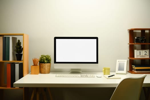 White blank screen computer monitor, houseplant and coffee cup on working table.