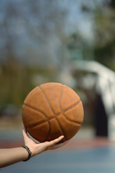 Close up of basketball player holding a ball on an outdoor court. People, sport and active lifestyle concept.