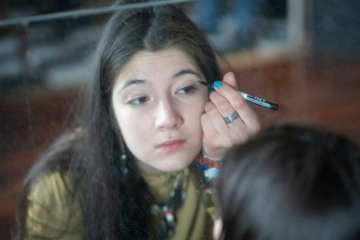 young beautiful woman applying makeup near the mirror