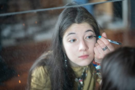 young beautiful woman applying makeup near the mirror