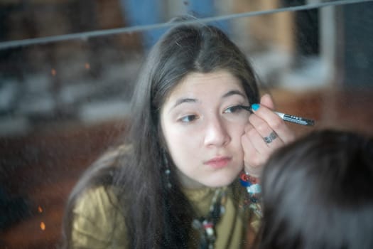 young beautiful woman applying makeup near the mirror