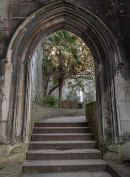 London, UK - Feb 27, 2024 - The stone arched entrance leads to the stone staircase inside of St Dunstan in the East Church Garden. The historic church was bombed and destroyed in the Second World War and is now a park, London city hidden places, Space for text, Selective focus.