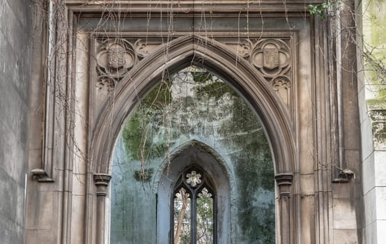 London, UK - Feb 27, 2024 - Perspective view of The stone arched entrance and Stone window frame inside of St Dunstan in the East Church Garden. The historic church was bombed and destroyed in the Second World War and is now a park, London city hidden places, Space for text, Selective focus.