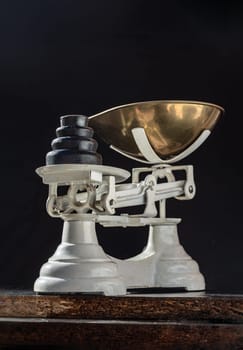 Classic weight scale Isolated on dark background. Old obsolete manual weighing scales and Iron Brass Tray with set of cast iron weights. Antique balance scales, Copy space, Selective Focus.