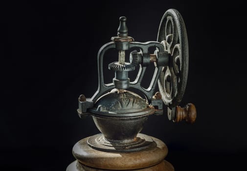 Detail of Old original coffee grinder metal shake wheel with hand crank on dark background. Close-up of Antique coffee bean original grinder, Copy space, Selective focus.