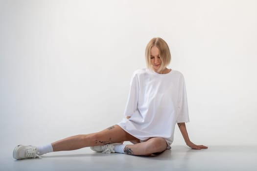 Beautiful girl in a white oversized t-shirt posing on a white background. High quality photo