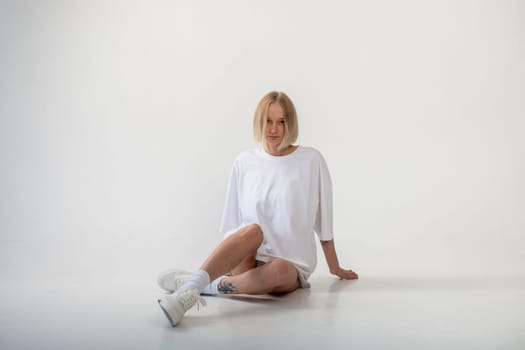 Beautiful girl in a white oversized t-shirt posing on a white background. High quality photo