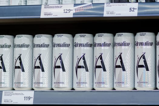 Tyumen, Russia-January 11, 2024: Aluminum cans of Adrenaline Zero Sugar energy drinks are neatly arranged on a supermarket shelf.