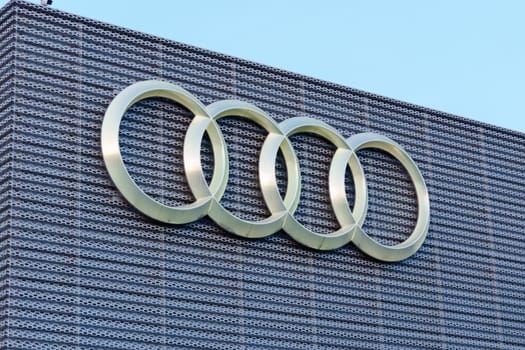 Tyumen, Russia-March 18, 2024: Audi Brand Logo on Gray Textured Wall, close up.
