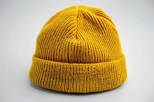 A yellow knitted hat laid flat on a white background, showcasing its intricate texture and vibrant color.
