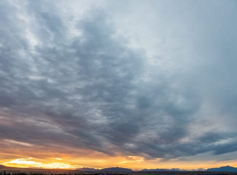 Stunning sunset with vivid hues over mountain outlines beneath a cloudy dusk.