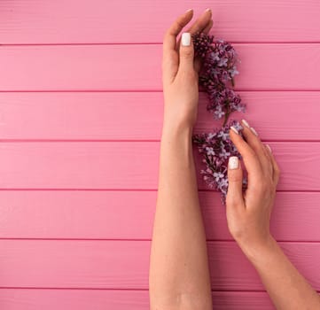 Summer abstract background mockup template free copy space for text pattern sample top view above pink wooden board. blank empty area for inscription. woman hand manicure hold blossom flowers lilac