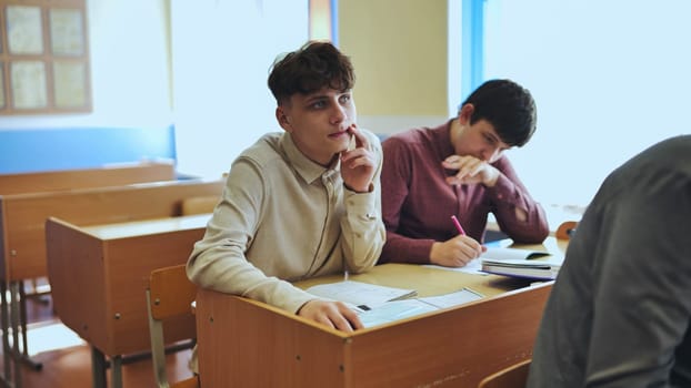 Schoolboys at a desk during class. The boy eats an apple