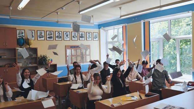 Students toss notebooks and books up in their classroom