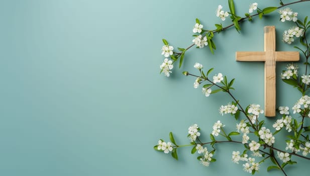 Wooden cross and white flowers on blue background with copy space.