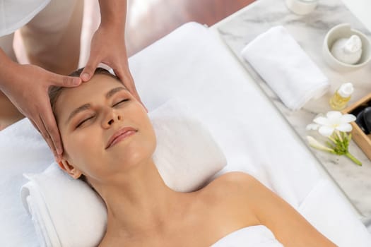 Panorama top view of woman enjoying relaxing anti-stress head massage and pampering facial beauty skin recreation leisure in dayspa modern light ambient at luxury resort or hotel spa salon. Quiescent