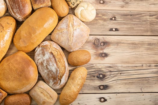 On the old wooden counter, the bakery store has gathered all the types of bread that it prepares in its bakery. View from above.