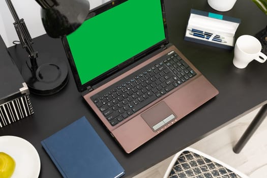 Corporate workplace with a laptop, calendar and pens prepared for a new employee. A new workplace with computer work. Green screen of the monitor.
