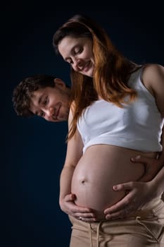 The husband and wife look at the large pregnancy belly and enjoy the fruit of their love immensely. Ninth month of pregnancy. Unborn baby in the belly.