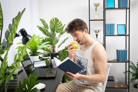 An employee sits at home and reviews a book calendar before starting work at the laptop. Remote work during a pandemic. A bright living room in a modern style with a preferable space.