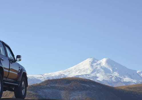 Travel concept with big 4x4 car against sunset and mountains. Closeup photo of offroad wheel.