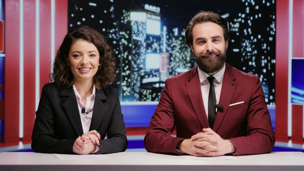 Reporters team hosting night show late to discuss about latest celebrity scandals in newsroom, covering all important topics on worldwide television network. Broadcasters hosts presenting breaking news.