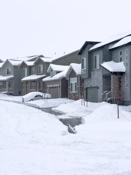 Castle Rock, Colorado, USA-March 16, 2024-The scene depicts a suburban tranquility with homes lining a street blanketed in snow, punctuated by a cleared path that weaves through the winter wonderland. The overcast sky promises more snow, creating a hushed atmosphere over the neighborhood.