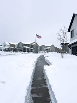 Castle Rock, Colorado, USA-March 16, 2024-Snow blankets a suburban street, where houses stand in quiet repose and driveways reveal the morning labor against the winter relentless drifts.