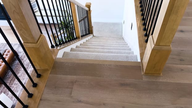 The image captures the detail of a well-designed modern staircase, lined with plush beige carpet, complemented by white walls and wooden balusters.