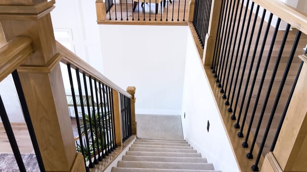 The image captures the detail of a well-designed modern staircase, lined with plush beige carpet, complemented by white walls and wooden balusters.